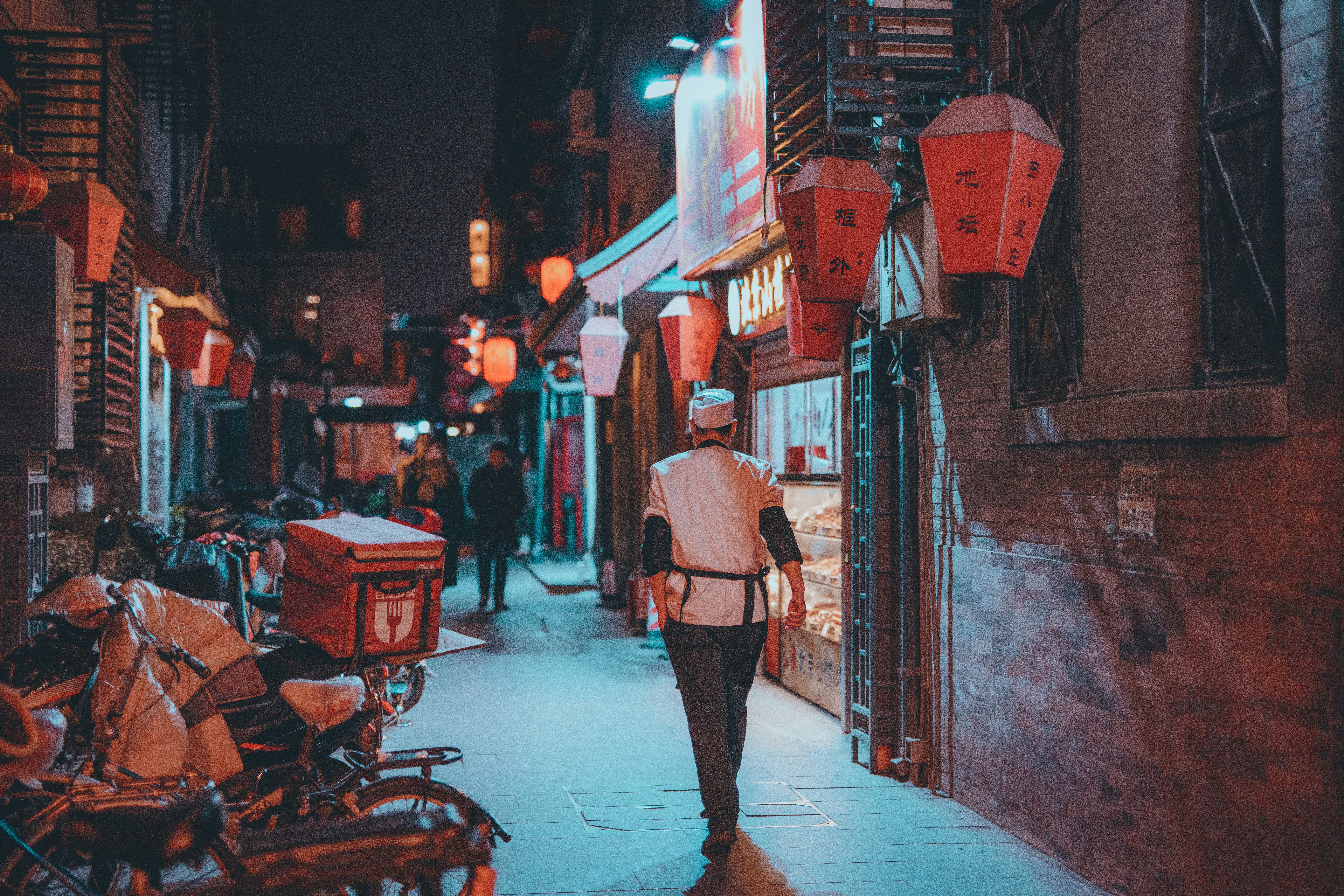 woman in pink coat walking on sidewalk during night time